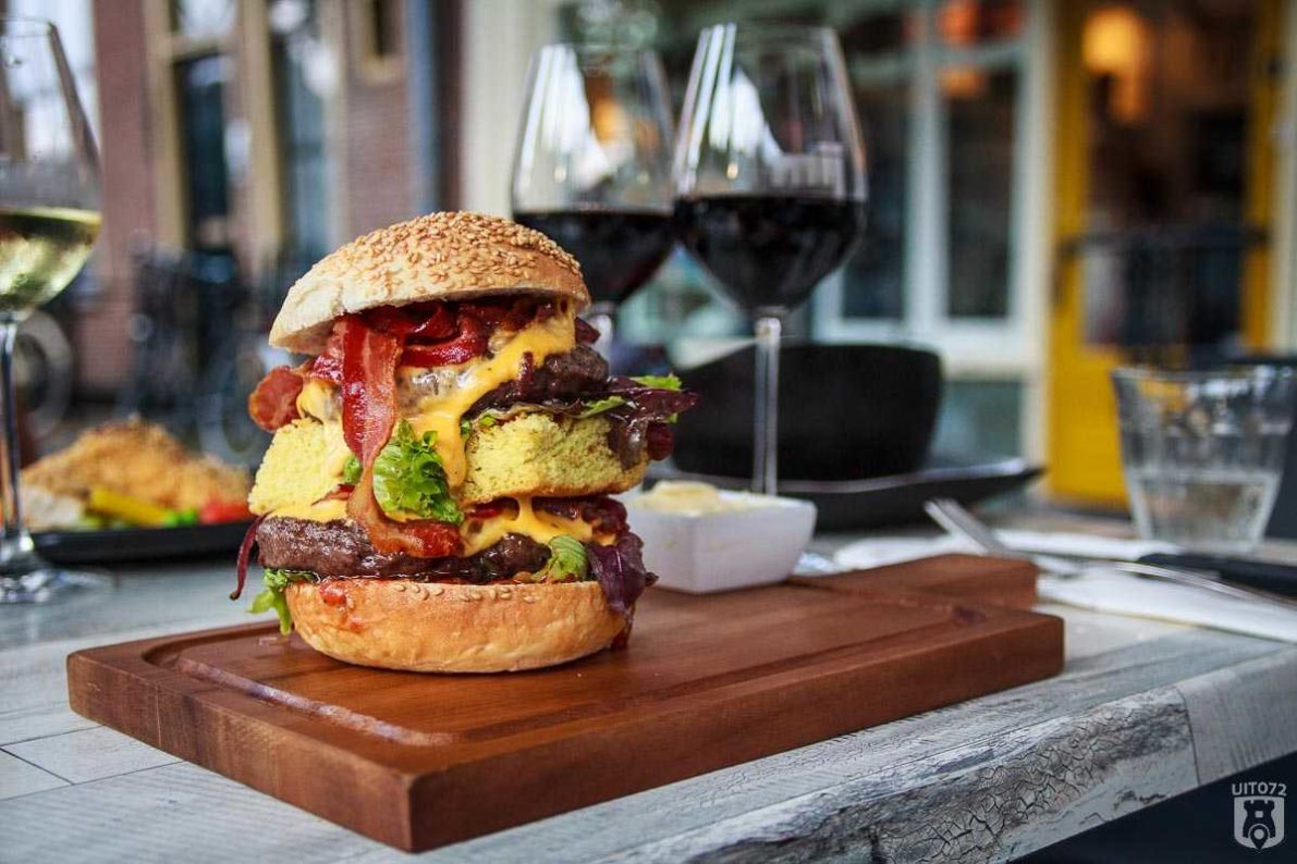 Hamburger van Wagyu-rund gerookt op Whiskeyhoutjes van de Yellow Egg, sesambroodje met uiencompote, pittige tomaten relish, bacon en cheddar cheese