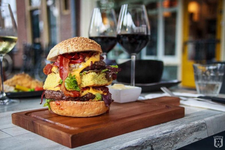 Hamburger van Wagyu-rund gerookt op Whiskeyhoutjes van de Yellow Egg, sesambroodje met uiencompote, pittige tomaten relish, bacon en cheddar cheese